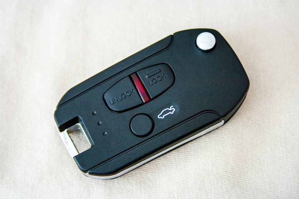 A black flip-key car fob with lock and unlock buttons