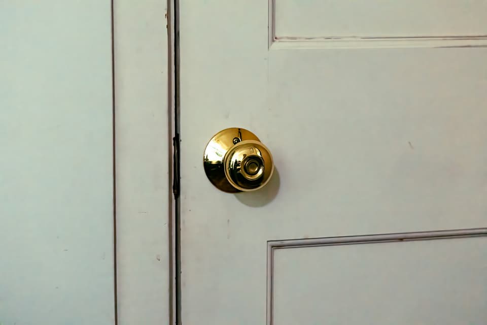 A brass doorknob on a white panelled door